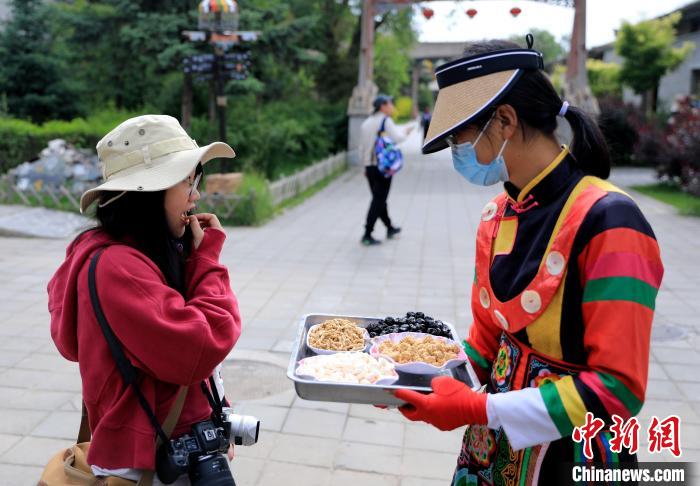 圖為身穿土族服飾的女性介紹當(dāng)?shù)靥厣〕??！⊙Φ?攝
