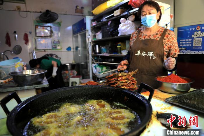 圖為平安驛·河湟民俗文化體驗地內(nèi)的商戶炸干板魚?！⊙Φ?攝