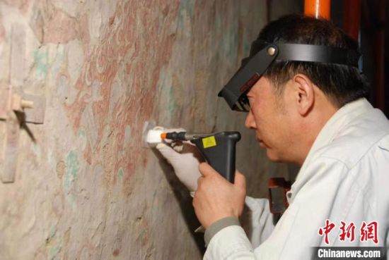 敦煌研究院研究員樊再軒進行壁畫修復。(資料圖)張云文 攝