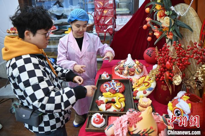 1月25日，隨著春節(jié)臨近，蘭州一花饃店“龍”元素花饃熱銷。圖為工作人員向顧客推薦“龍”元素花饃。九美旦增 攝</p><p>