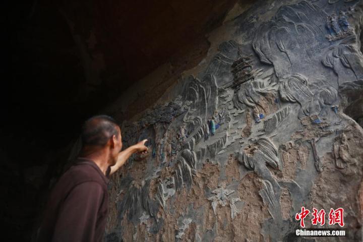 7月15日，甘肅省平?jīng)鍪袥艽h百里石窟長廊羅漢洞石窟內(nèi)，該窟文保員郭建平介紹窟內(nèi)石刻彩繪壁畫。郭建平家中三代人曾自發(fā)保護羅漢洞石窟。羅漢洞石窟遺存40余個窟龕，以北魏至清代風(fēng)格為主。中新社記者 李亞龍 攝