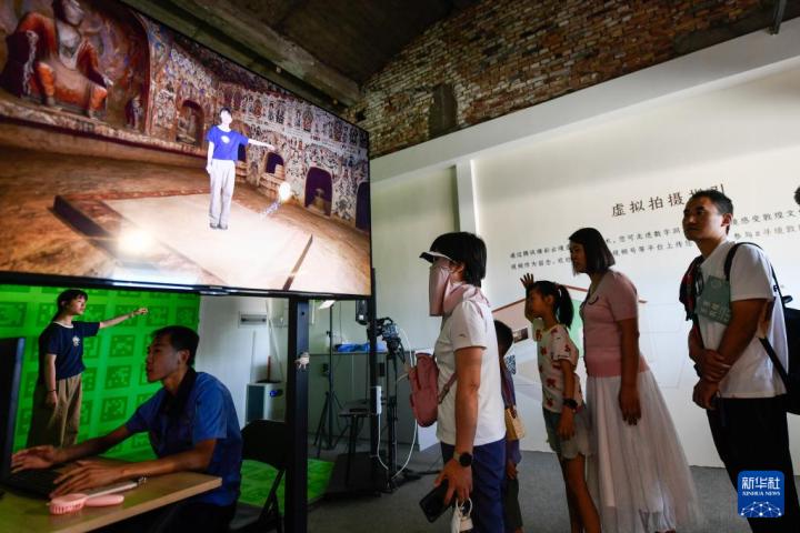 7月22日，游客體驗(yàn)“尋境敦煌——數(shù)字敦煌沉浸展”后，在虛擬演播廳拍攝一段真人與洞窟虛擬場景交互的視頻。新華社記者 郎兵兵 攝</p>
<p>
