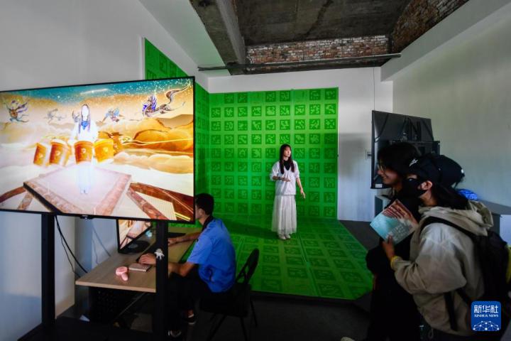 7月22日，游客體驗(yàn)“尋境敦煌——數(shù)字敦煌沉浸展”后，在虛擬演播廳拍攝一段真人與洞窟虛擬場景交互的視頻。新華社記者 郎兵兵 攝</p>
<p>